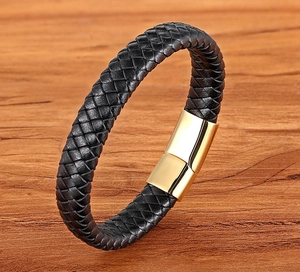Close-up of black braided leather bracelet with a polished gold magnetic clasp on wood