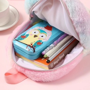 Plush unicorn mini backpack interior showing space for stationery, pens, and notebooks