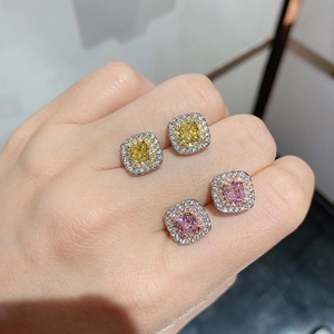 Close-up of square-cut yellow and pink zircon earrings with halo setting on fingers