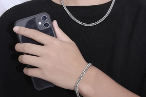 Close-up of minimalist silver stainless steel cuban chain bracelet worn by male model