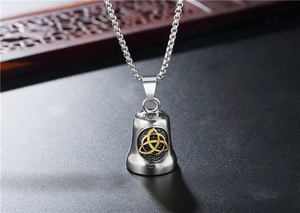 Macro detail of vintage Viking bell pendant with gold Celtic Triquetra on steel chain