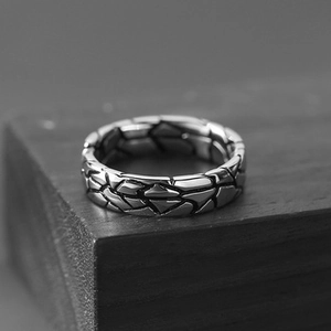 Detailed view of silver punk bracelet with geometric scale textures on dark wood