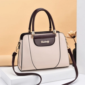 Minimalist beige and burgundy leather shoulder bag with gold hardware on exhibition stand