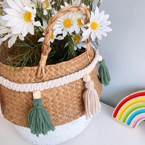 Detail of woven straw basket with colorful tassels, wooden beads and white daisy flowers