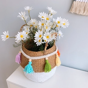 Close-up of woven straw basket with colorful tassels and white daisy flowers