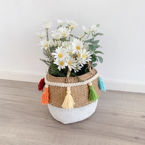 Detail of bohemian seagrass basket with colorful tassels, wooden beads and white daisies