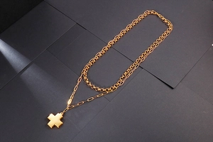 Detail of double-layer gold cross necklace featuring a mirror-finish cross pendant
