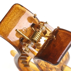 Detailed close-up of translucent amber hair claw clip with golden metal spring