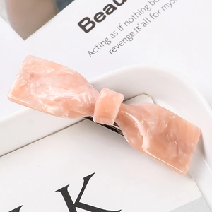 Detailed macro view of a pink marble acetate bow hair claw clip on a white decorative plate