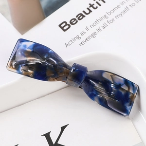 Detailed view of a dark blue marble textured acetate hair claw in a bow design