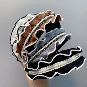 Detail of knitted ruffle headbands with inlaid pearls and gold woven chain trim