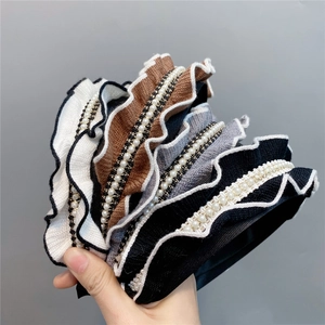 Close-up of pleated knit headbands with pearl accents in black and multiple colors