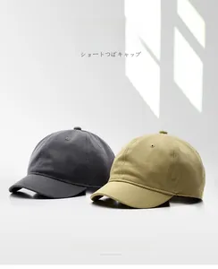 Vue détaillée de casquettes à bord court en coton de couleur gris foncé et jaune moutarde