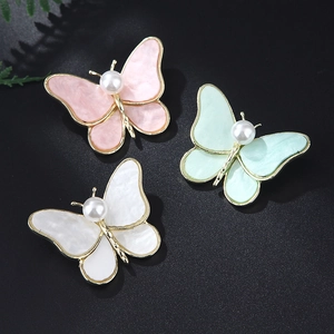 Detail of three alloy butterfly brooches with marble texture wings and pearls