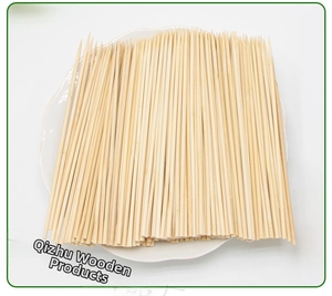 Close-up of smooth natural bamboo skewers for BBQ and fruit stacked on a white plate