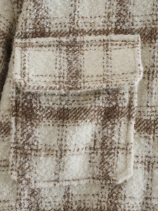 Gros plan macro montrant le tissu en tweed épais à carreaux beige et marron et la poche