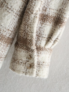 Détail de chemise en flanelle à carreaux montrant la texture et les poignets boutonnés