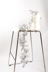 Detail of silver Christmas garland with glitter berries and artificial leaves on a chair