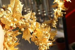 Close-up of sparkling gold artificial holly leaves and berries Christmas vine decoration