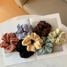 Flat lay of colorful satin hair scrunchies in Morandi tones on a minimalist background