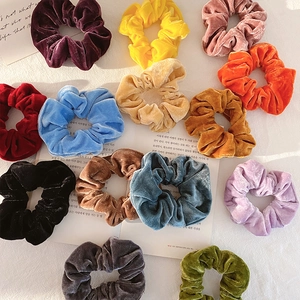 Velvet hair scrunchies in various vibrant colors set against a minimalist white background