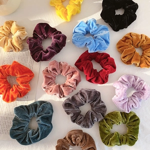 Set of colorful velvet scrunchies in various shades on a minimalist fashion magazine base