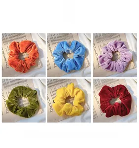Detailed view of six colorful velvet scrunchies displayed on newspaper background