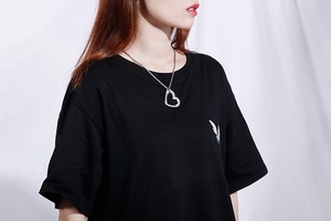 Gros plan d'un collier avec pendentif cœur évidé en cristal porté sur un t-shirt noir