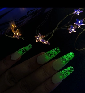 Glow-in-the-dark long trapezoid nail art with green luminous stars and hearts in dark