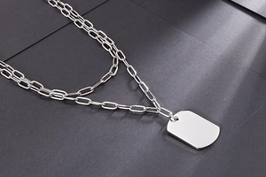 Close-up of a double-layered silver stainless steel necklace with a polished military tag