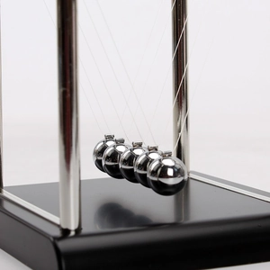 Classic Newton's cradle with five silver metal balls and a black base on a grey background