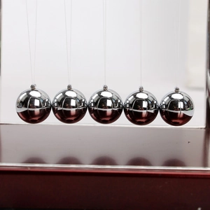 Front view of five silver metal Newton's cradle balls on a dark red wooden base