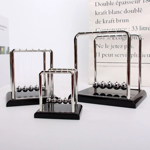 Detailed set of three Newton's cradles in various sizes on a minimalist office desk