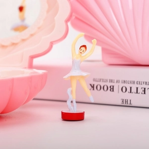 Detail of a rotating ballet girl figurine inside a pink shell musical jewelry box