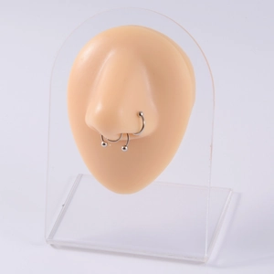 Silver nose rings and U-shaped septum jewelry displayed on a silicone model with acrylic stand