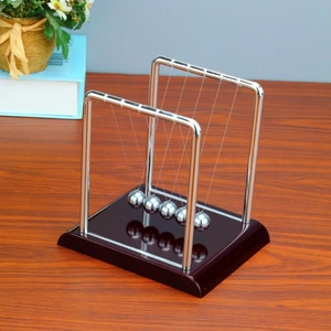Close-up of Newton's cradle with metal balls and brown wooden base on a desk