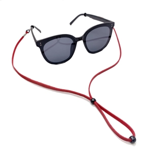Detail eines roten verstellbaren Brillenbands an einer schwarzen Sonnenbrille