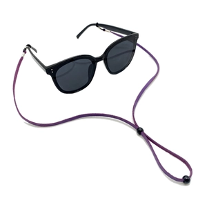 Detail eines verstellbaren lila Wildleder-Brillenbands an einer schwarzen Sonnenbrille