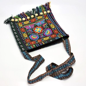 Detailed close-up of ethnic embroidered crossbody bag with colorful tassels and beads