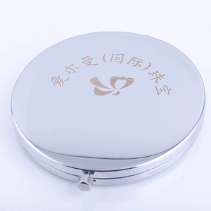 Macro view of a round silver metallic makeup mirror featuring engraved floral patterns
