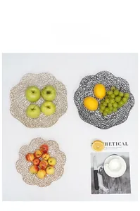 Detail of wave-edged metal wire fruit basket in black and gold finishes with fresh fruits