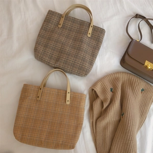 Detail of vintage brown plaid canvas tote bags with premium leather handles and rivets