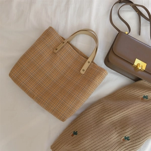 Flat lay of vintage plaid tote bag with brown leather accents and embroidered sweater