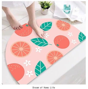 Semicircular bath mat with orange patterns on a tile floor showing soft absorbent texture