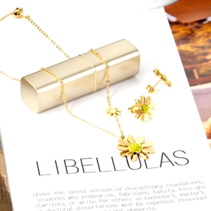 Détail de parure bijoux marguerite dorée avec cristaux jaunes sur support épuré