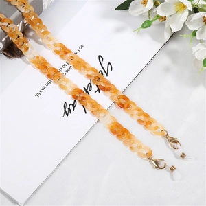 Amber acrylic mask and glasses chain with golden lobster clasps on a white floral background