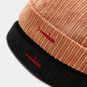 Close-up of corduroy texture and red embroidery on brown and black beanie hats