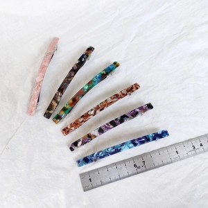 Detailed set of six 10cm acetate hair clips in assorted patterns on white linen fabric