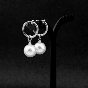 Detailed view of silver hoop earrings featuring white faux pearls on a black T-stand