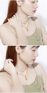 Detail of a layered golden heart pendant necklace and ball stud earrings on model